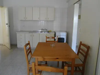 a kitchen with a wooden table and chairs in it at Terpsithea Apartments in Ayia Napa