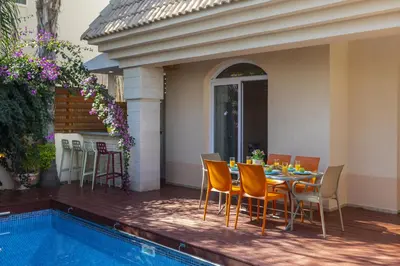 a table and chairs on a deck next to a pool at Protaras Villa Rocco in Paralimni