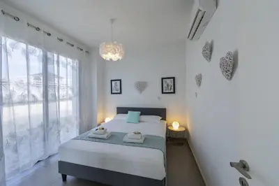 a bedroom with a bed and a large window at Protaras Greco Hilltop Views in Protaras