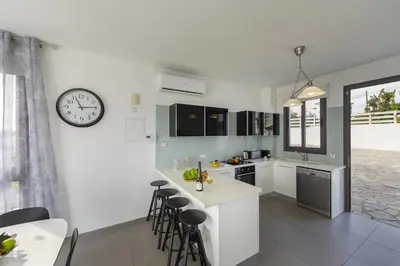 a kitchen with a clock on a white wall at Protaras Greco Hilltop Views in Protaras