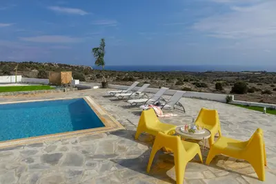 a swimming pool with yellow chairs and a table and a swimming pool at Protaras Greco Hilltop Views in Protaras