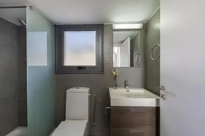 a bathroom with a toilet and a sink and a window at Protaras Greco Hilltop Views in Protaras