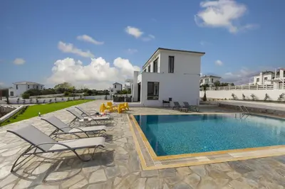 a swimming pool with lounge chairs and a house at Protaras Greco Hilltop Views in Protaras