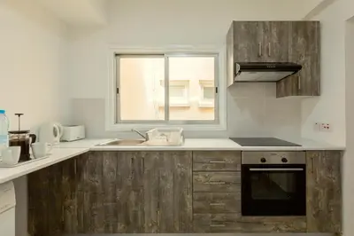 a kitchen with wooden cabinets and a sink and a window at Savvas City Centre Flat in Larnaka
