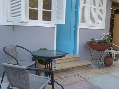 a patio with a table and chairs and a blue house at Sparrows Nest in Larnaka