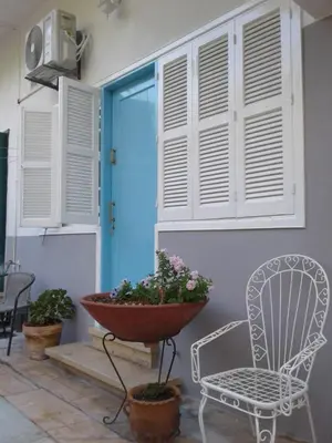 a porch with a chair and a blue door at Sparrows Nest in Larnaka