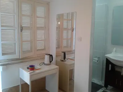 a bathroom with white shutters and a sink at Sparrows Nest in Larnaka