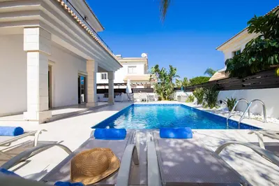 a swimming pool with a table and chairs next to a house at Villa Malama in Paralimni