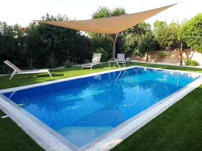 a swimming pool in a yard with a umbrella over it at Villa Bouboulina Cyprus in Ayia Napa