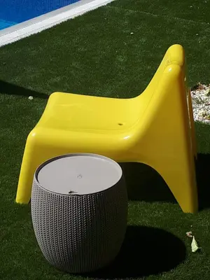 a yellow chair and a trash can on the grass at Villa Bouboulina Cyprus in Ayia Napa