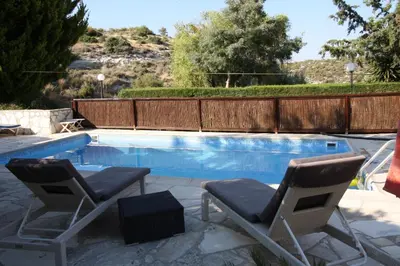 a pair of chairs sitting next to a swimming pool at Swimmers' Paradise in Pissouri