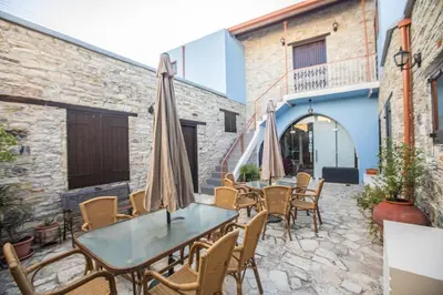 a patio with tables and chairs and umbrellas at Iosiphis Stonebuilt House in Pano Lefkara