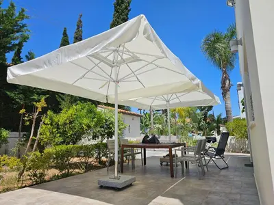 a white umbrella on a patio with a table and chairs at FAMILY HOME in Protaras