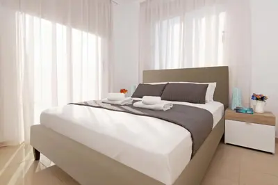 a white bedroom with a large bed with two white towels at Villa Eden in Ayia Napa