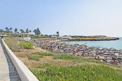 a beach with umbrellas and people sitting on the beach at Villa Eden in Ayia Napa