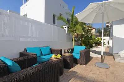 a patio with wicker chairs and an umbrella at Villa Eden in Ayia Napa