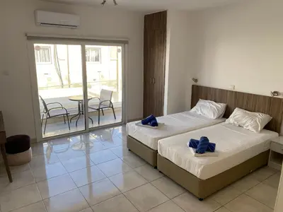 a bedroom with two beds and a balcony with a table at Midtown Napa Apartments in Ayia Napa