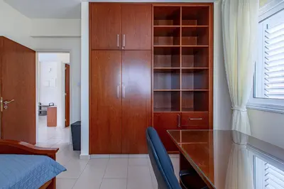 a bedroom with a bed and a desk and cabinets at Villa Nova in Protaras