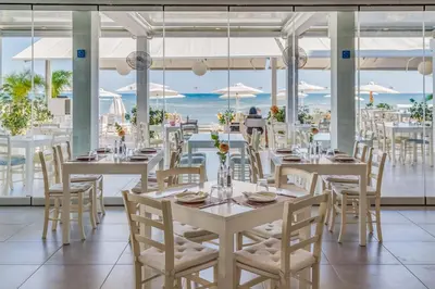 a restaurant with tables and chairs with the ocean in the background at Island Boutique Hotel in Larnaka