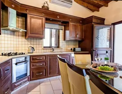a kitchen with wooden cabinets and a table with a plate of food at Villa Elizabeth in Limassol