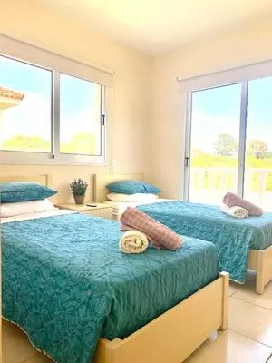 a bedroom with two beds and two windows at Villa Oceania in Ayia Napa