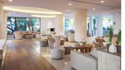 a lobby with white chairs and tables and windows at Alasia Boutique Hotel in Limassol