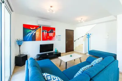 a living room with a blue couch and a tv at Villa Francesca in Paralimni