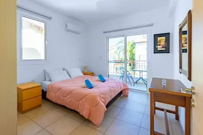 a bedroom with a bed and a desk and windows at Villa Francesca in Paralimni
