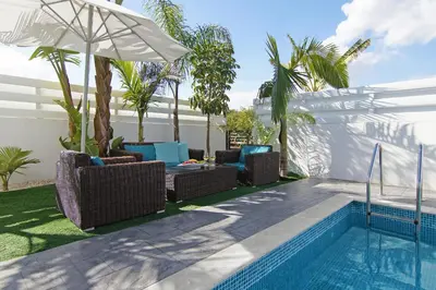 a pool with wicker chairs and an umbrella next to a pool at Villa Serena in Protaras