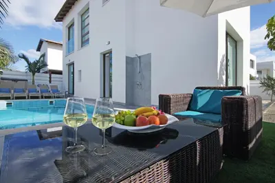 a table with a bowl of fruit and two glasses of wine at Villa Serena in Protaras