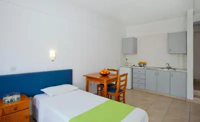 a bedroom with a bed and a table and a kitchen at Paloma Hotel Apartments in Ayia Napa