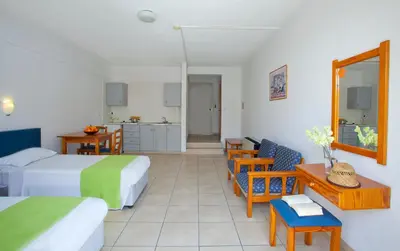 a hotel room with two beds and a table and chairs at Paloma Hotel Apartments in Ayia Napa