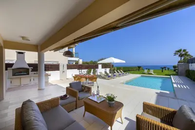 a patio with a couch and chairs and a swimming pool at Protaras Beachfront Villa Pietra in Protaras