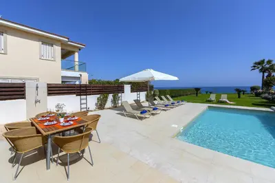 a patio with a table and chairs next to a swimming pool at Protaras Beachfront Villa Pietra in Protaras