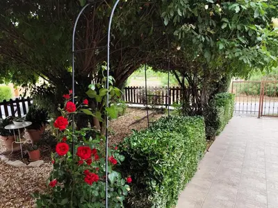 an arbor with red flowers in a garden at Roses Villa in Trimiklini