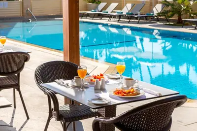 a table with food and drinks next to a swimming pool at Kapetanios Limassol Hotel in Limassol