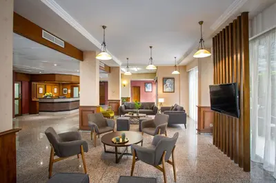 a lobby with a waiting room with chairs and a tv at Kapetanios Limassol Hotel in Limassol