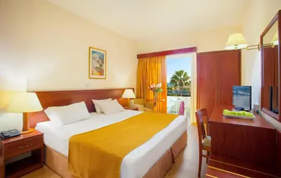 a bedroom with a bed and a desk with a television at Kapetanios Limassol Hotel in Limassol