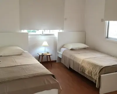 a bedroom with two beds and a table with a lamp at RESIDENCE ONE in Limassol