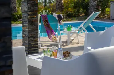 a table and chairs next to a swimming pool at Faros BeachFront Villa in Pervolia
