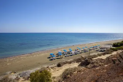 a beach with chairs and umbrellas and the ocean at Faros BeachFront Villa in Pervolia