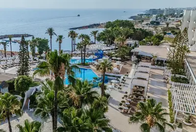 an aerial view of a resort with palm trees and the ocean at Golden Coast Beach Hotel in Protaras