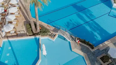 an overhead view of a swimming pool with a palm tree at Golden Coast Beach Hotel in Protaras