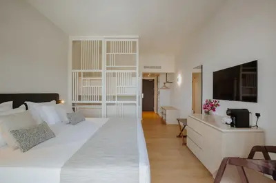 a bedroom with a large white bed and a desk at Golden Coast Beach Hotel in Protaras
