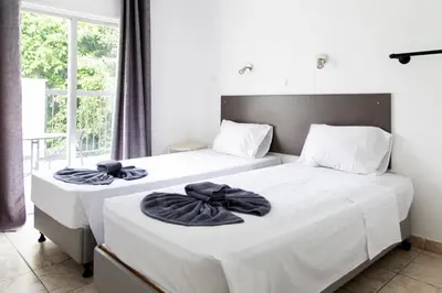 two beds in a room with white sheets and black towels at Summer's Hotel Apartments in Ayia Napa