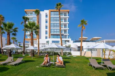 two people sitting in lawn chairs in front of a building at Leonardo Crystal Cove Hotel & Spa – Adults only in Protaras