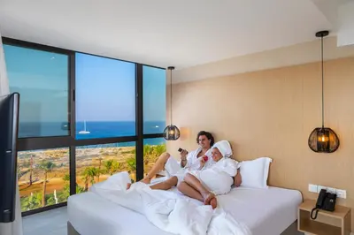 two women sitting on a bed in a hotel room at Leonardo Crystal Cove Hotel & Spa – Adults only in Protaras