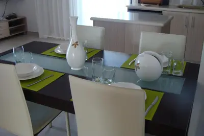 a dining room table with chairs and a table with plates and glasses at Polyxenia Isaak Luxury Villas and Apartments in Protaras