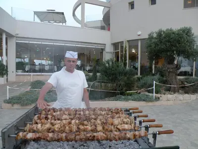 a man is cooking chickens on a grill at Polyxenia Isaak Luxury Villas and Apartments in Protaras
