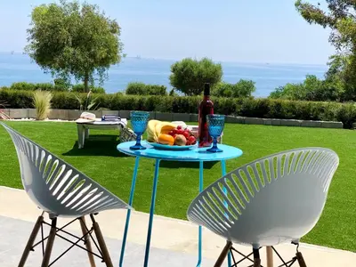 a table with a plate of fruit and a bottle of wine at Governors Beach Costas Apts in Governors Beach